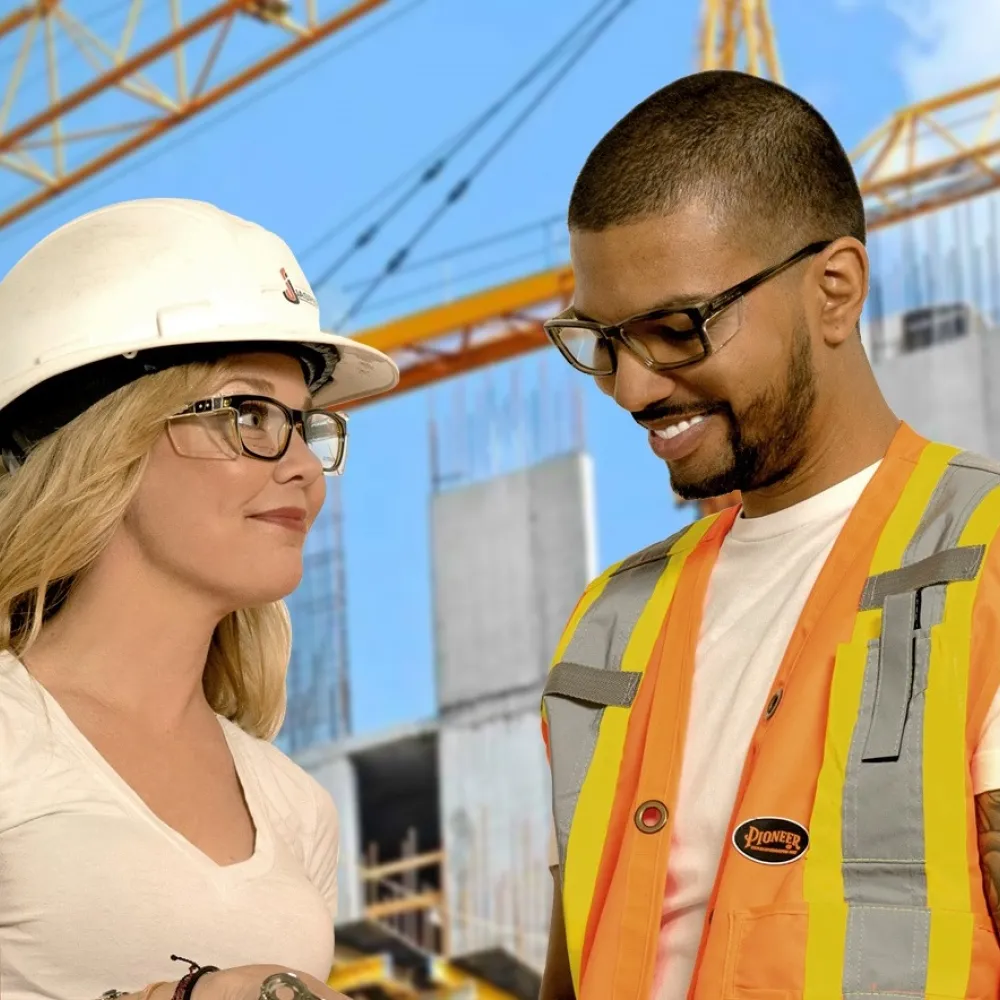Two construction workers at a job site wearing safety glasses.