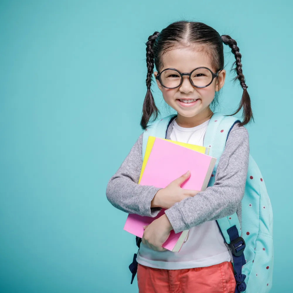 Kindergarten girl wearing a backpack and glasses. 