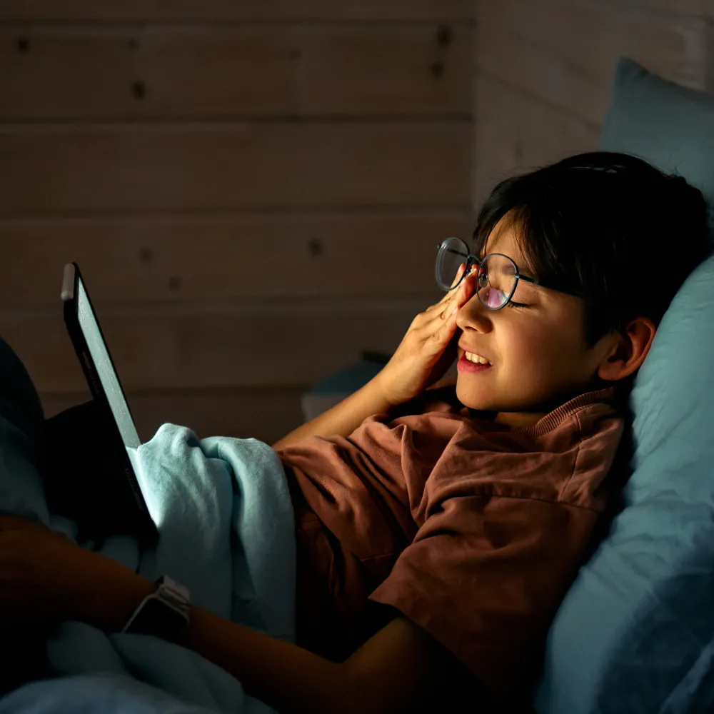 Child watching a tablet and rubbing their eyes. 